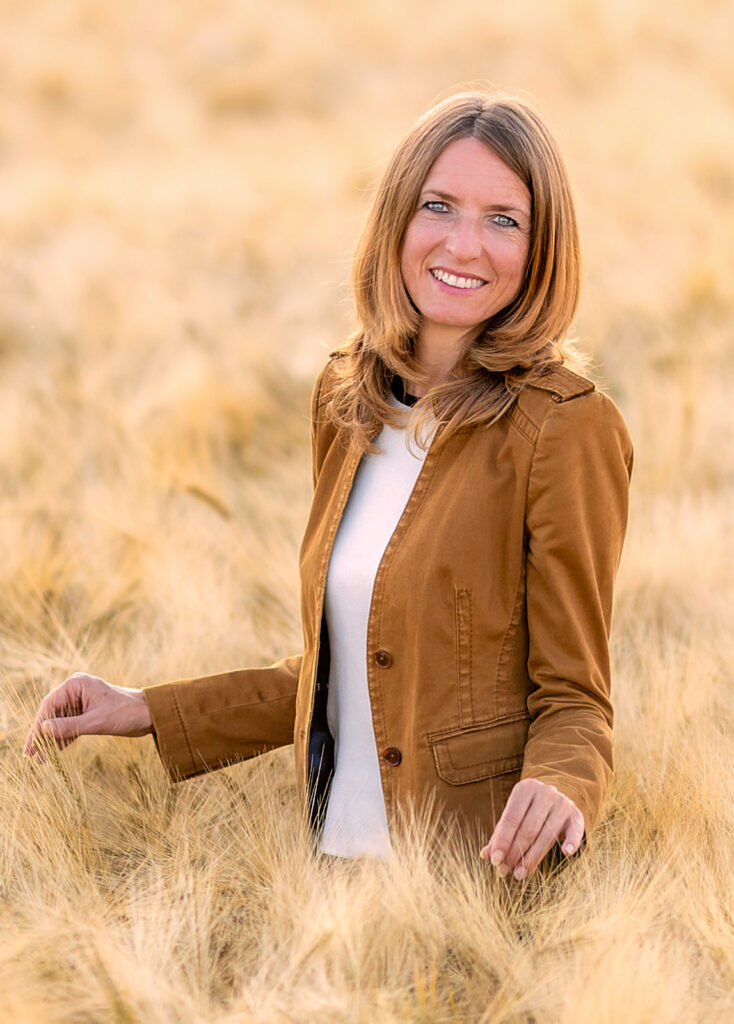 Inga Noetel - Coach für Persönlichkeitsentwicklung, Energiemedizin, Online-Coaching - Portrait im Gerstenfeld als Symbol der Ernte von Fülle