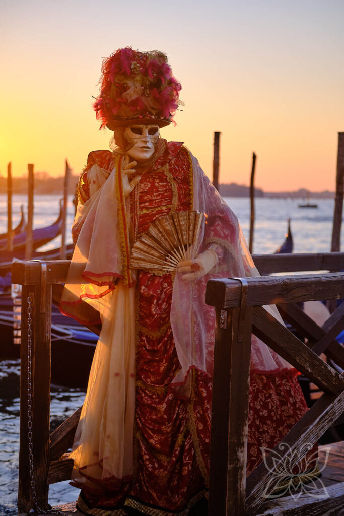 Karneval in Venedig - Person mit Kostüm und Maske bei Sonnenaufgang am Bootsanleger