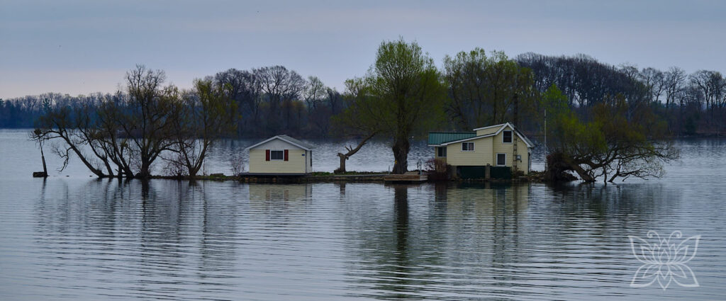 Einzelne Häuser auf einer winzigen Insel im See, die aussehen, als wären sie von einer Überflutung umgeben