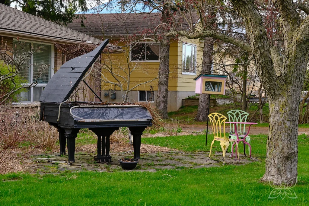 Altes Piano und bunte Stühle im Garten eines Hauses