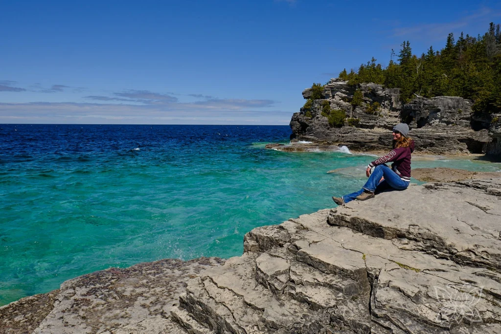 Coach Inga Noetel an türkiser Bucht mit Felsen und Tannen im Bruce Peninsula Nationalpark