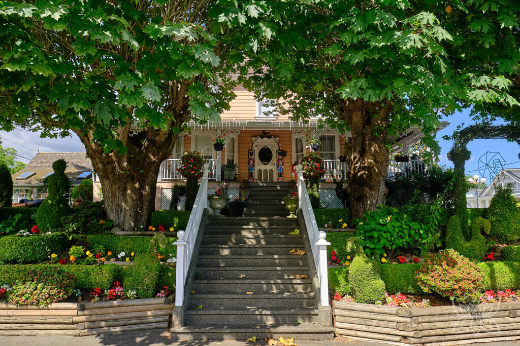 Gelbes Haus mit Bäumen und kunstvollem Garten.