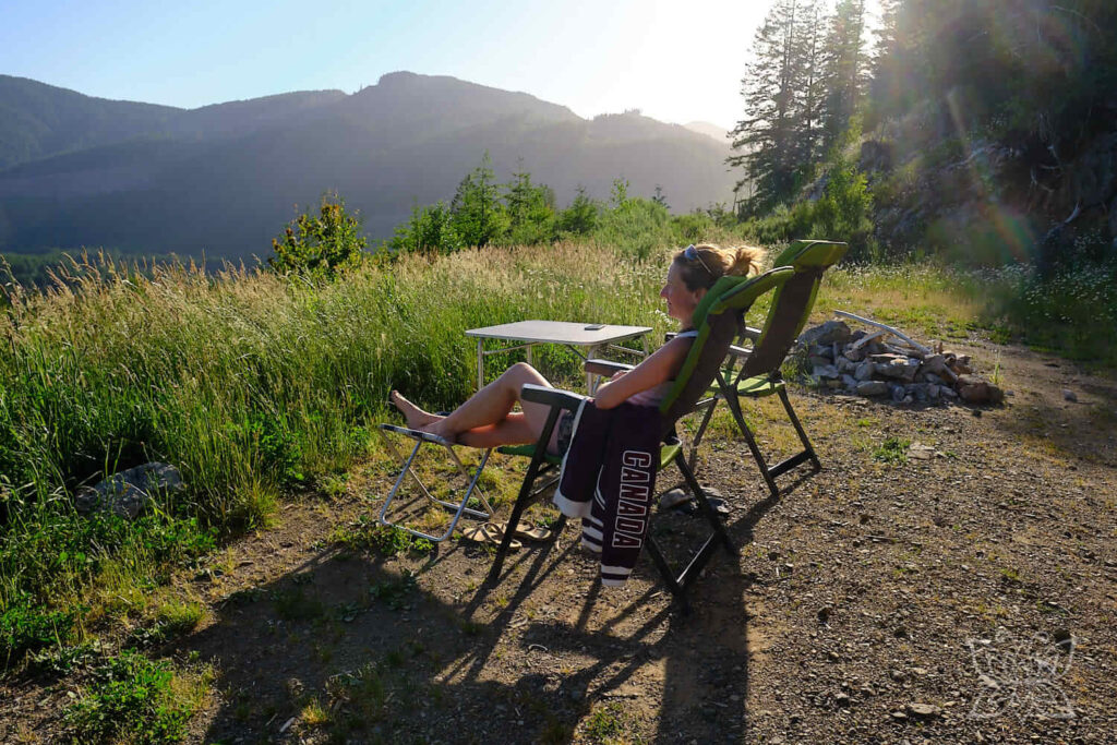 Inga im Campingstuhl auf einer Anhöhe mit Blick auf die umgebende bergige Landschaft