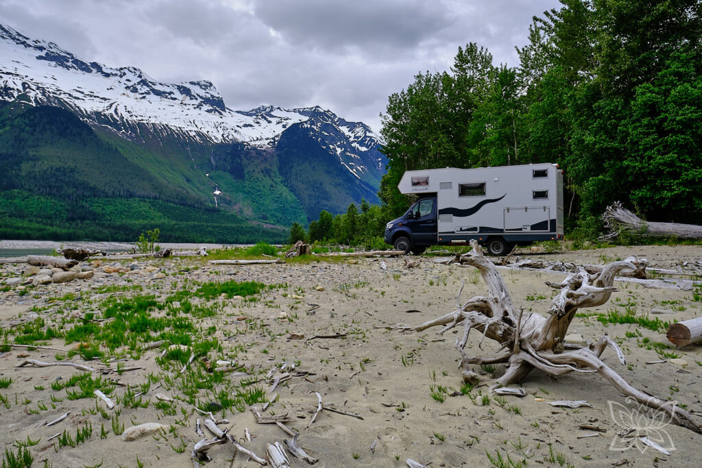 Bimobil HD 420 am Strand mit schneebedeckten Bergen im Hintergrund