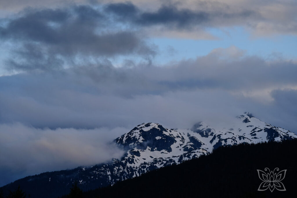 Eine Wolkenfront zieht über eine schneebedeckte Bergkuppe