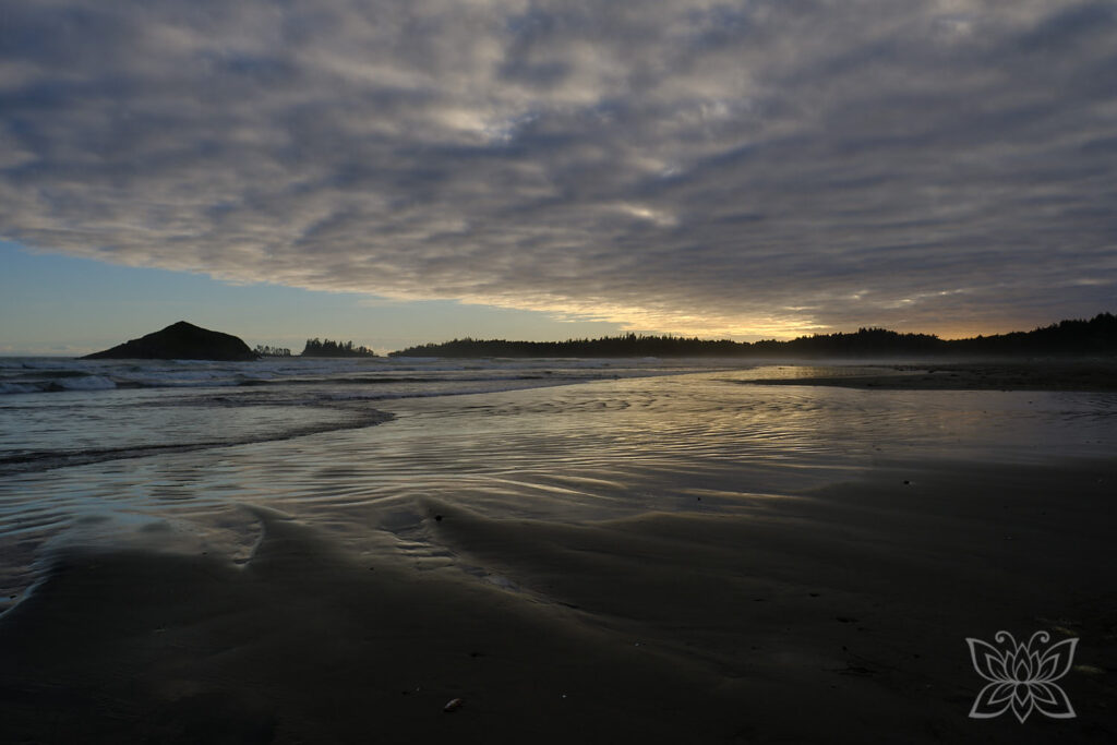 Sonnenuntergang am Strand mit Lichtreflektionen am gewellten Strand