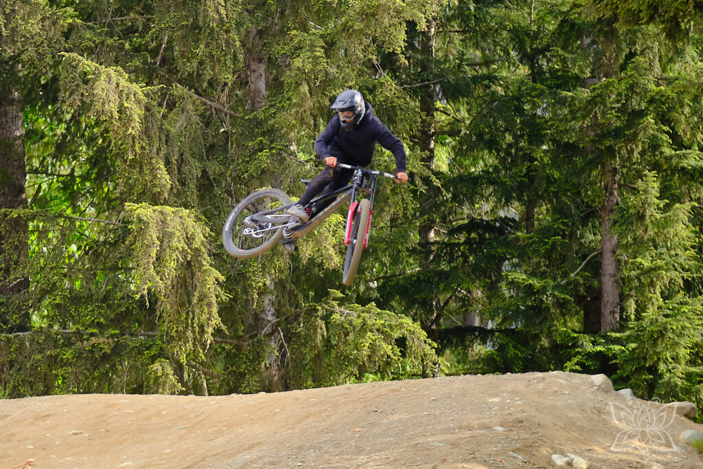 Über eine staubige Rampe springender Mountainbiker im Bikepark von Whistler